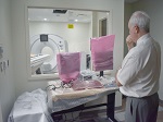 An older man in a white shirt and grey slacks is overlooking the new hospital equipment.
